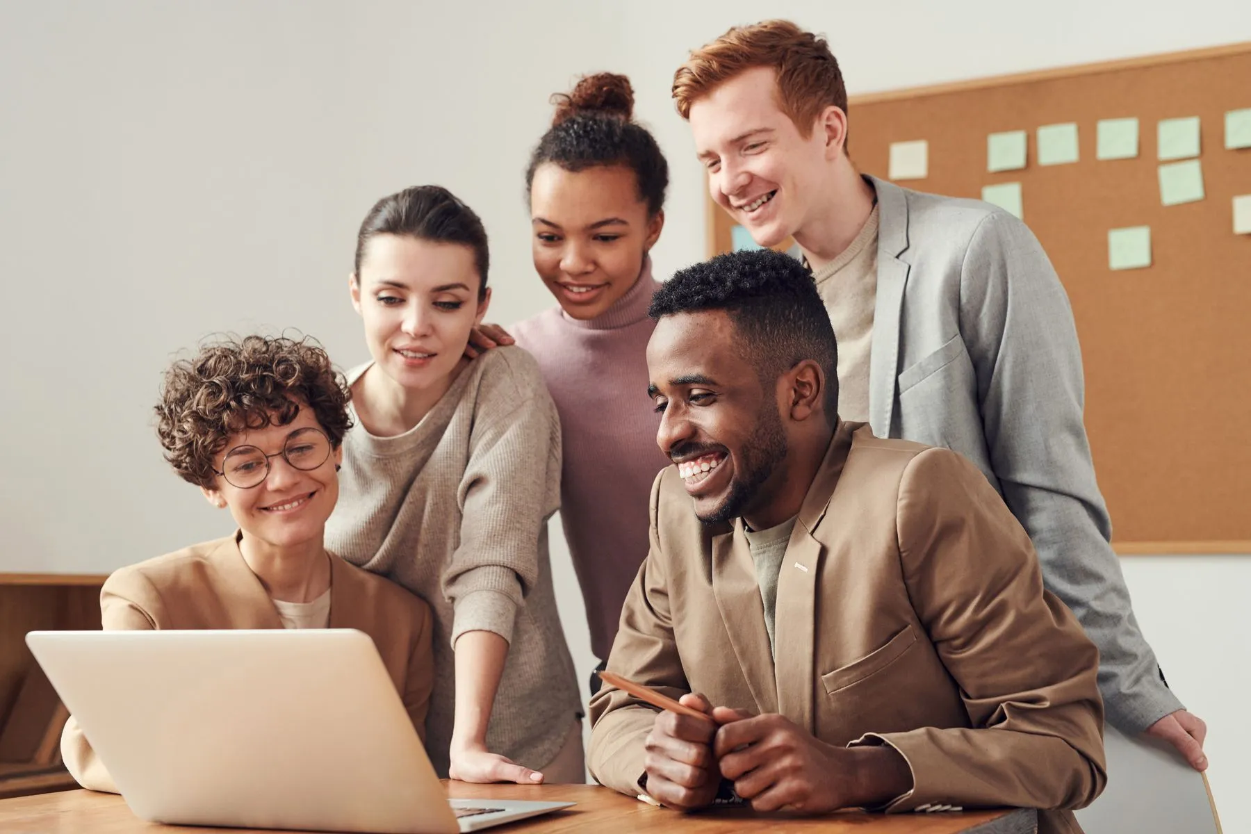 Equipe reunida e sorrindo em volta de um notebook
