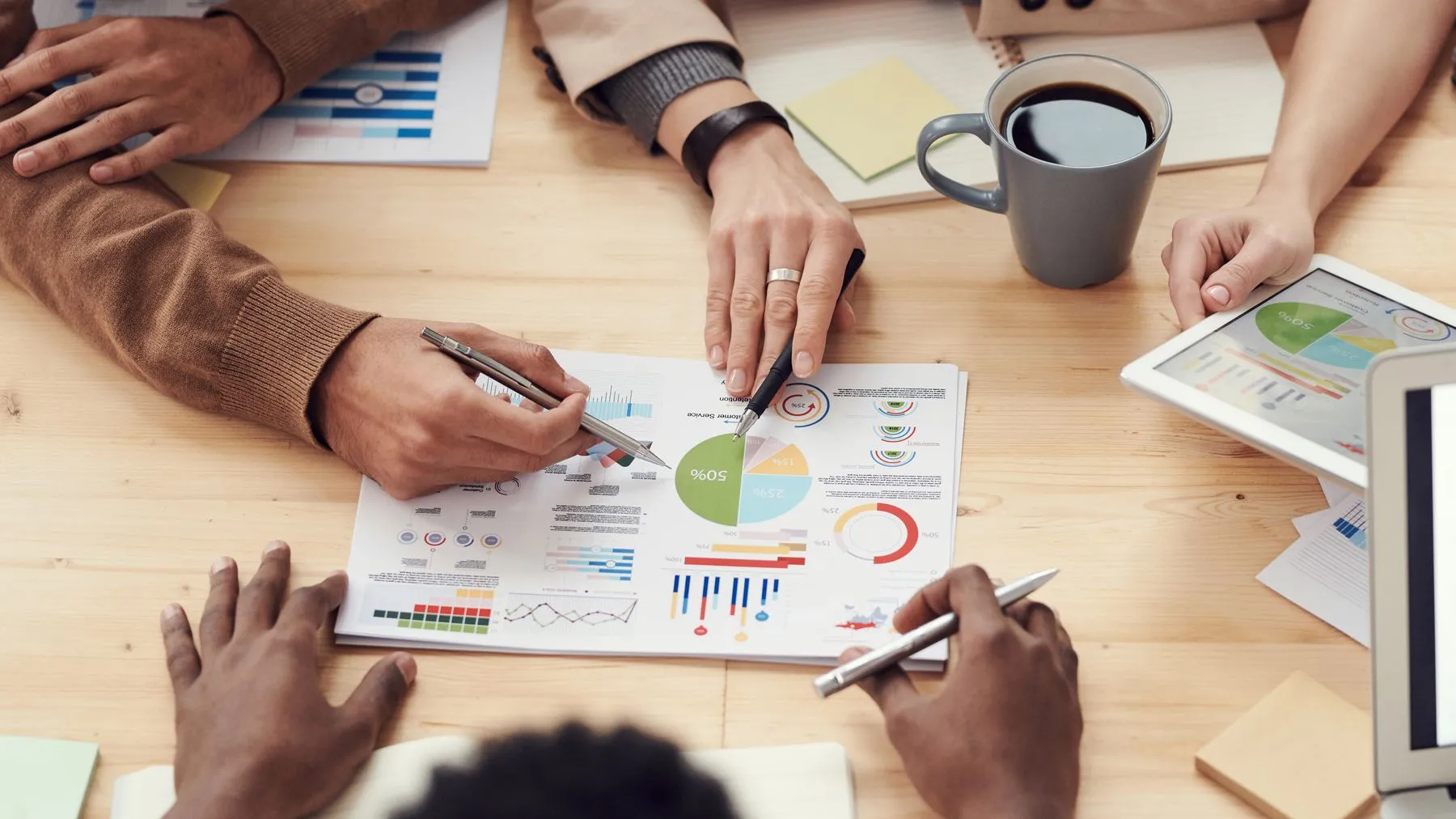 Mãos apontando para gráficos impressos em uma reunião