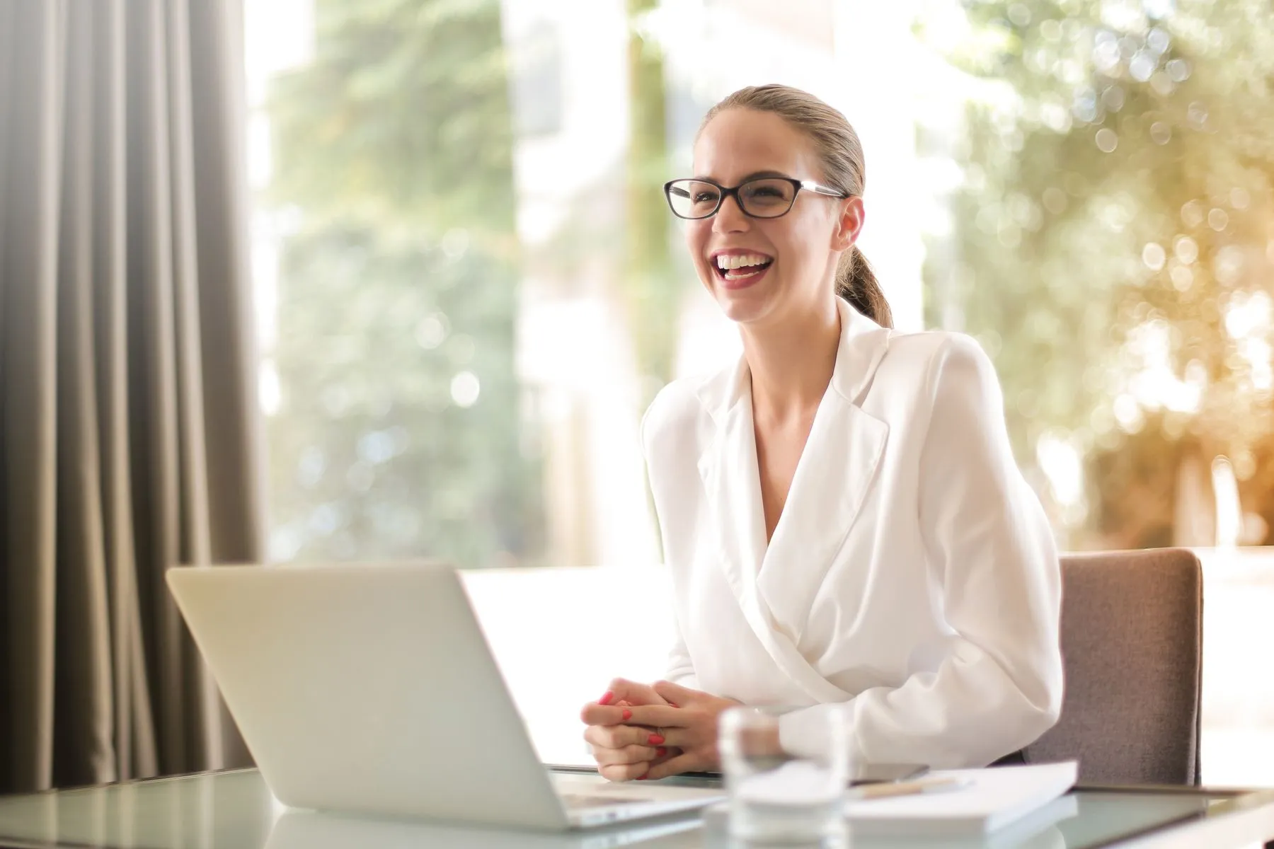 Contadora sorrindo enquanto atende um cliente pelo notebook